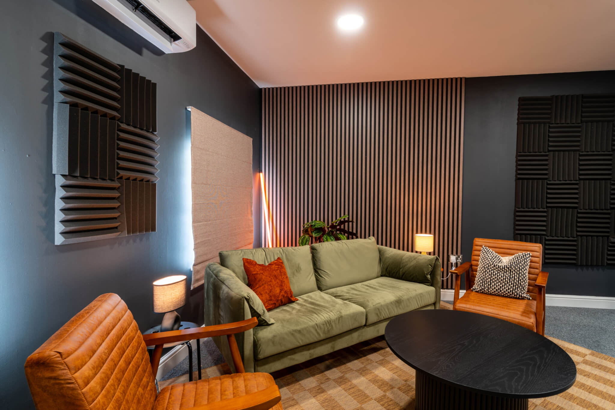 Image shows Superfly Marketing's brand new Podcast Studio: A fully equipped, soundproof studio with green sofa, 2 armchairs and a coffee table, enabling laid back in-house content creation.