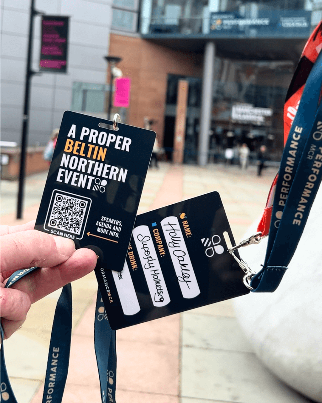 Image shows Charlie and Holly's QR Code lanyards for access to the PERFORMANCE MCR event. The tag line on the lanyards reads: "A PROPER BELTIN NORTHERN EVENT".